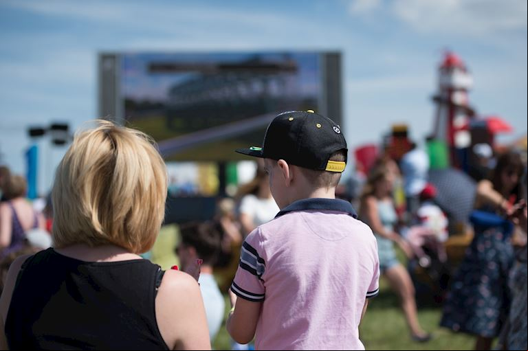 Family watching the big screens on the hill